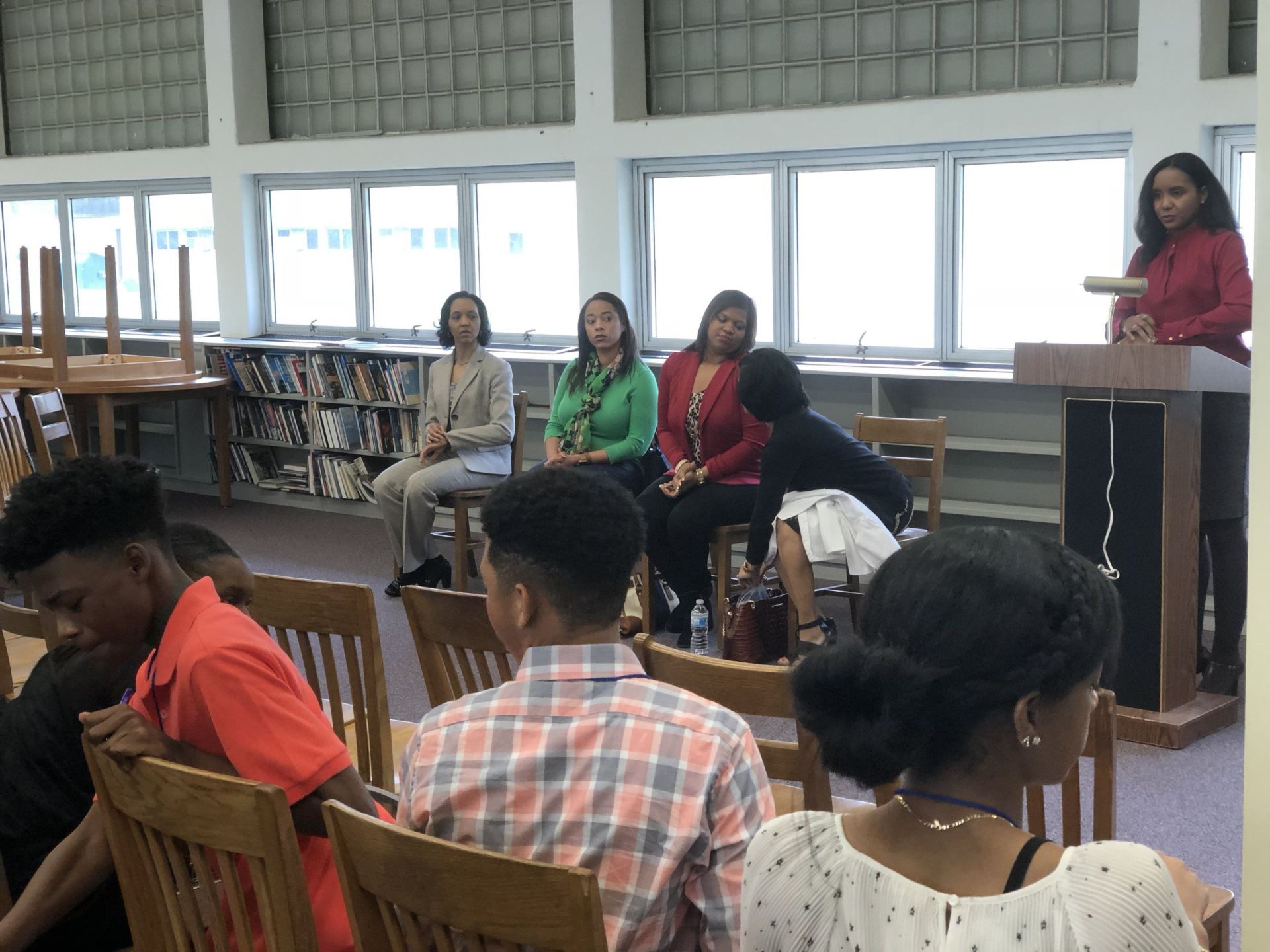 A woman is giving a speech to a group of people in a library.