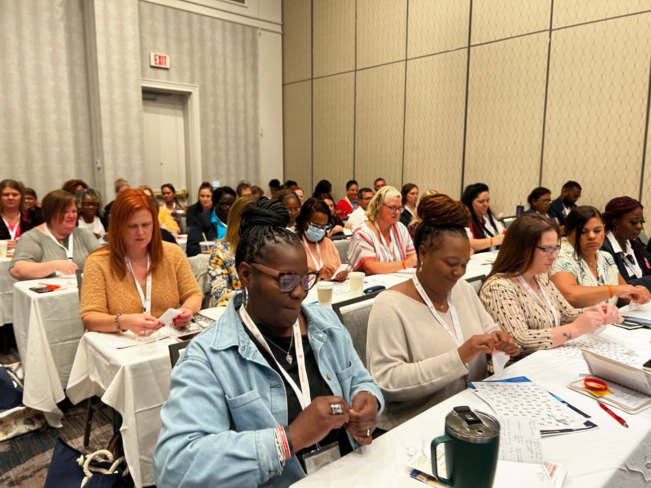 A large group of people are sitting at tables in a conference room.