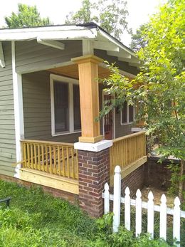 A small house with a porch and a white picket fence.