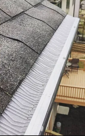 A close up of a gutter on a roof next to a deck.