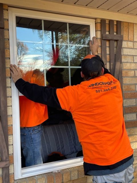 Two men standing on a ladder working on a window