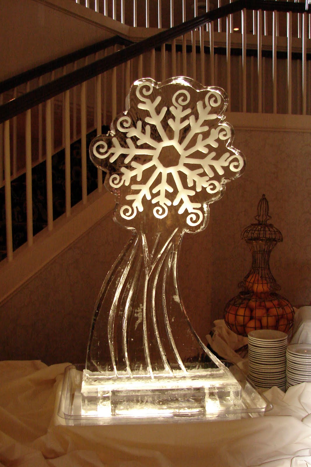 An ice sculpture of a snowflake is sitting on a table in front of a staircase.