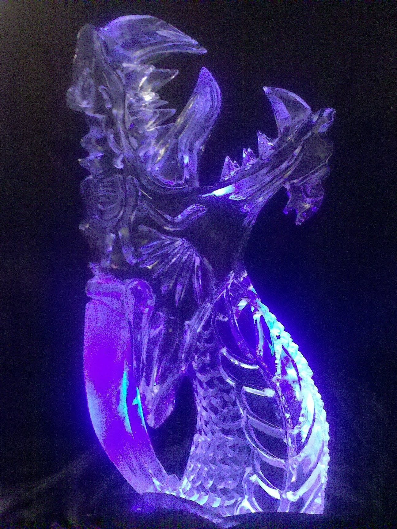 A statue of a dragon is lit up with purple lights.