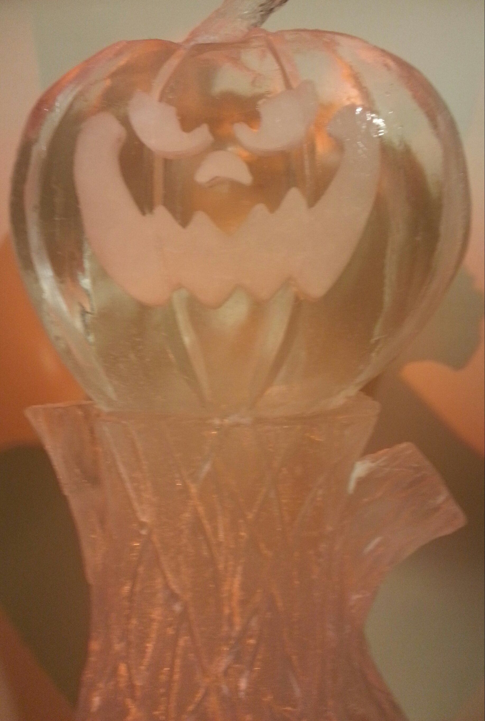 A close up of a glass pumpkin sitting on top of a vase.