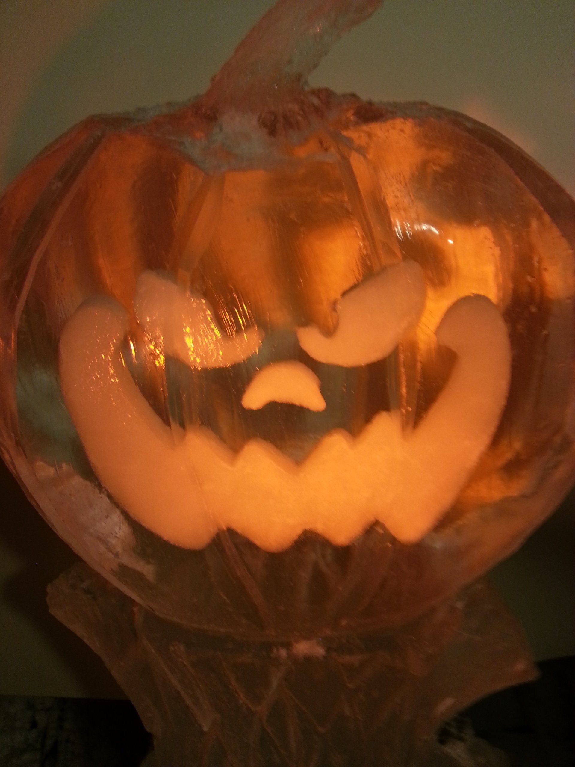 A glass pumpkin with a face carved into it