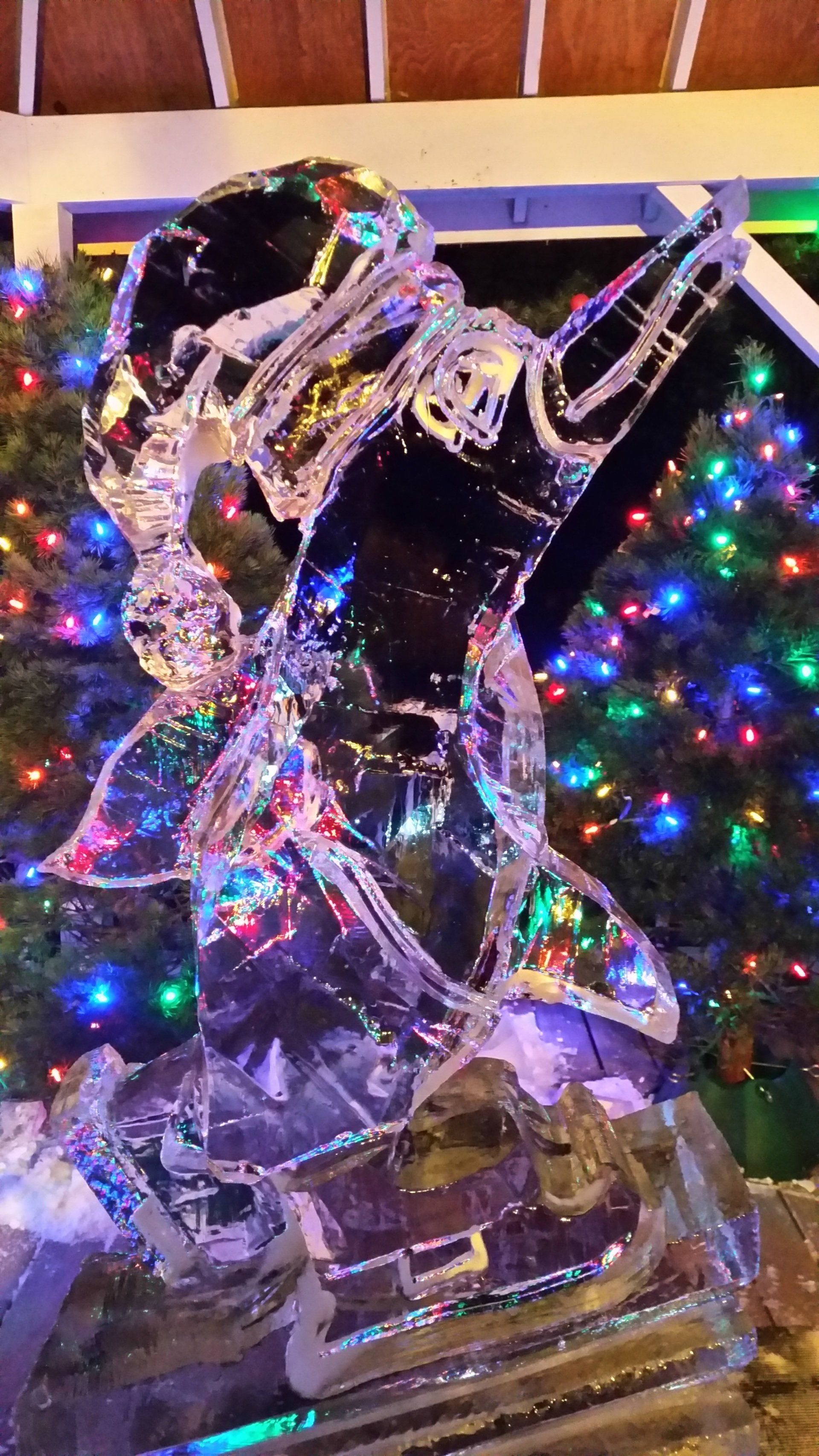 A close up of an ice sculpture in front of a christmas tree.