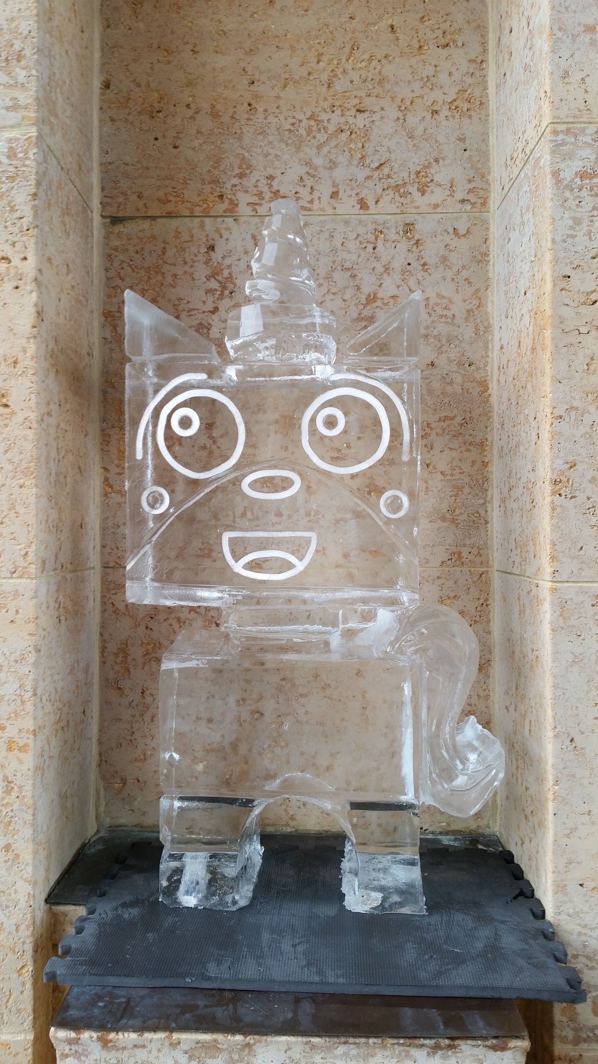 A statue of a robot made of ice is sitting on a table.