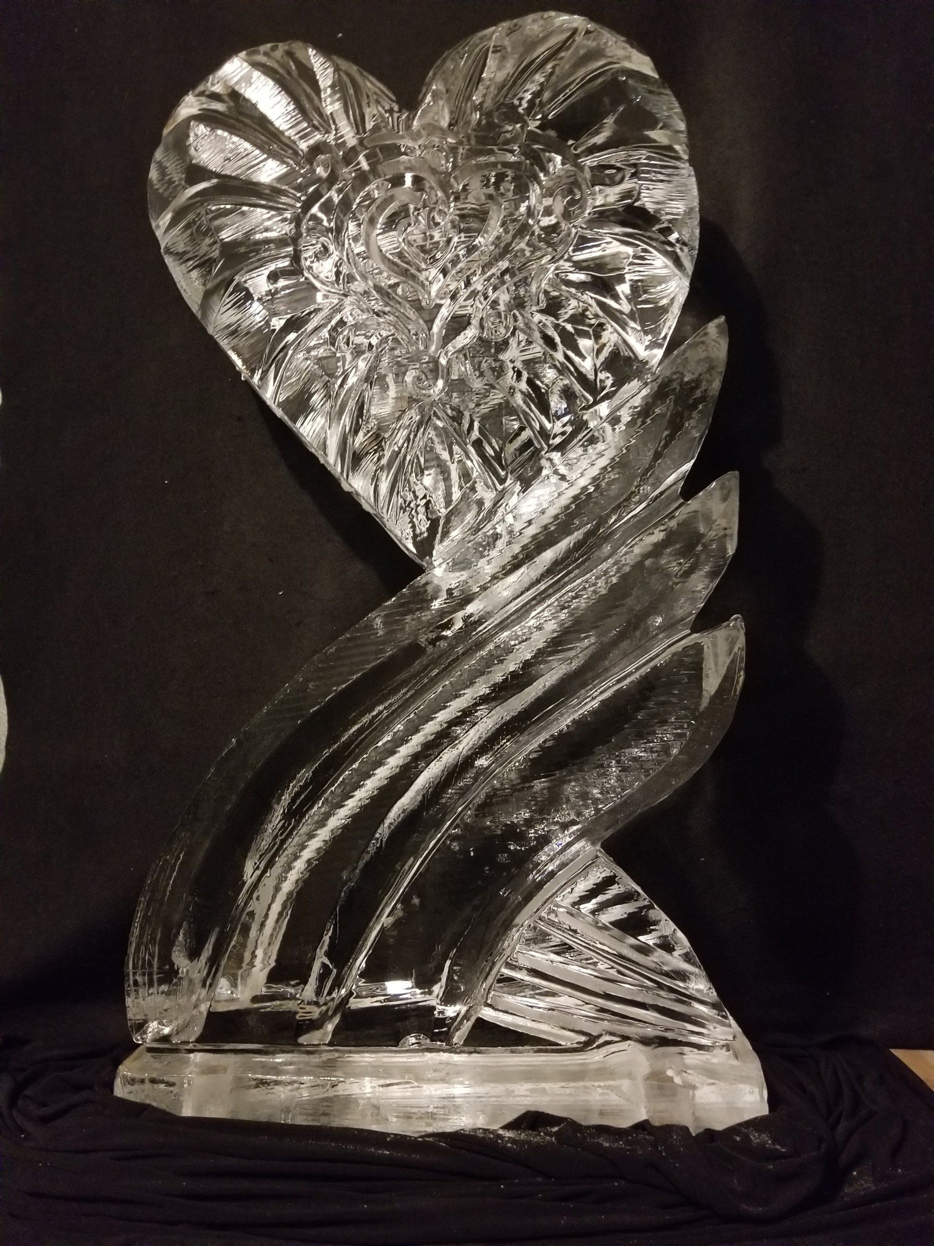 A heart shaped ice sculpture with a black background