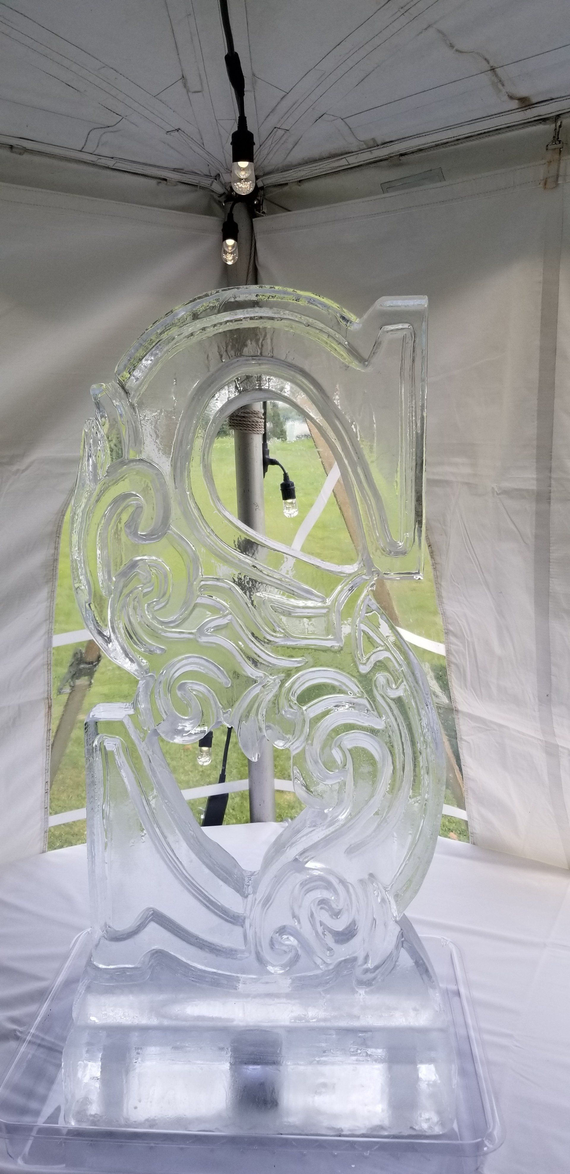 A large ice sculpture is sitting on top of a table under a tent.