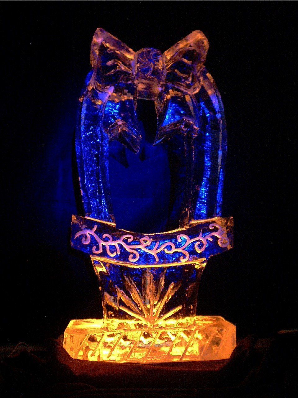 A glow in the dark ice sculpture of an owl with a banner on it