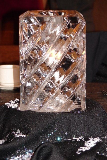 A clear block of ice sits on a black cloth on a table