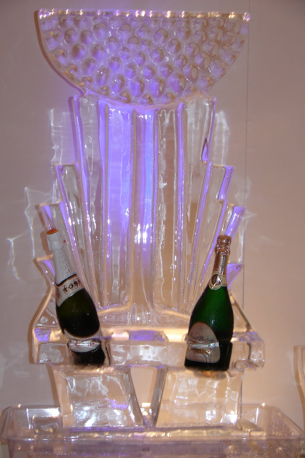 Two bottles of champagne are sitting on top of a ice sculpture.
