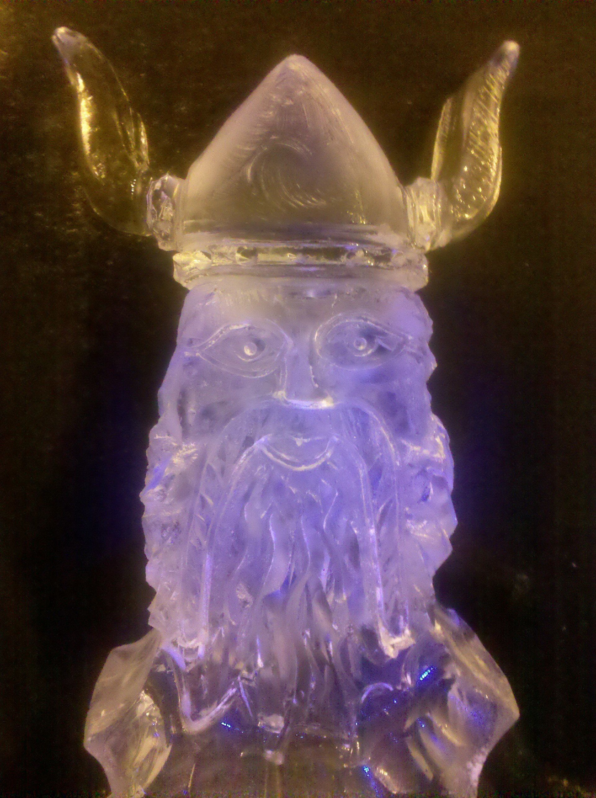 A statue of a viking with a beard and horns made of ice.
