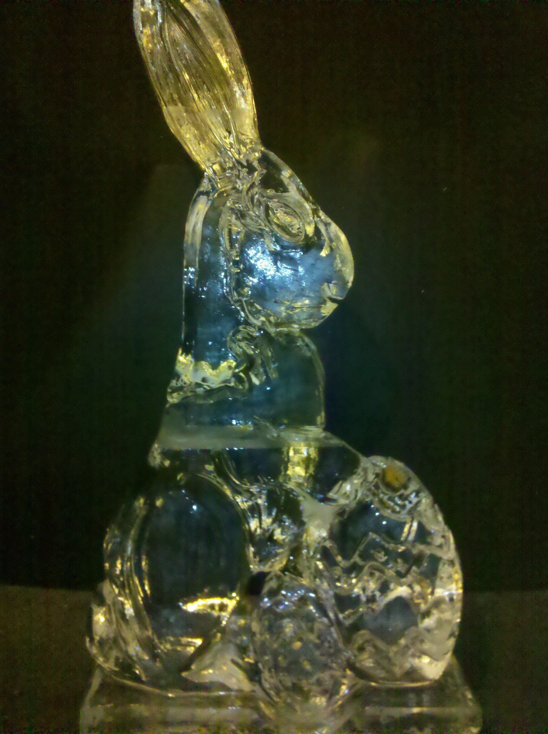 A clear glass rabbit sitting on top of an easter egg