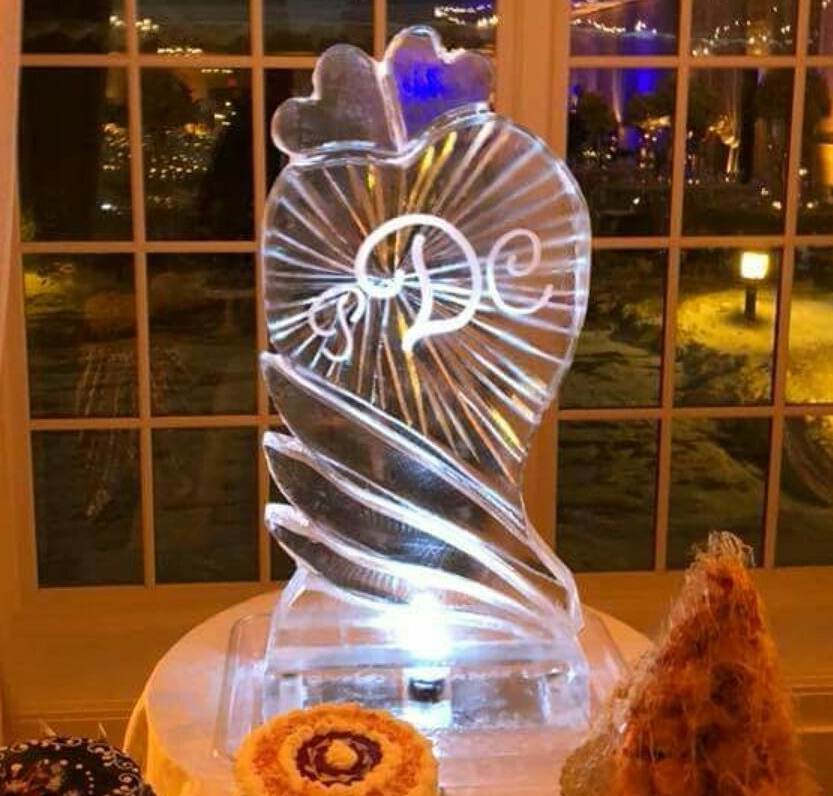 A heart shaped ice sculpture with a monogram on it