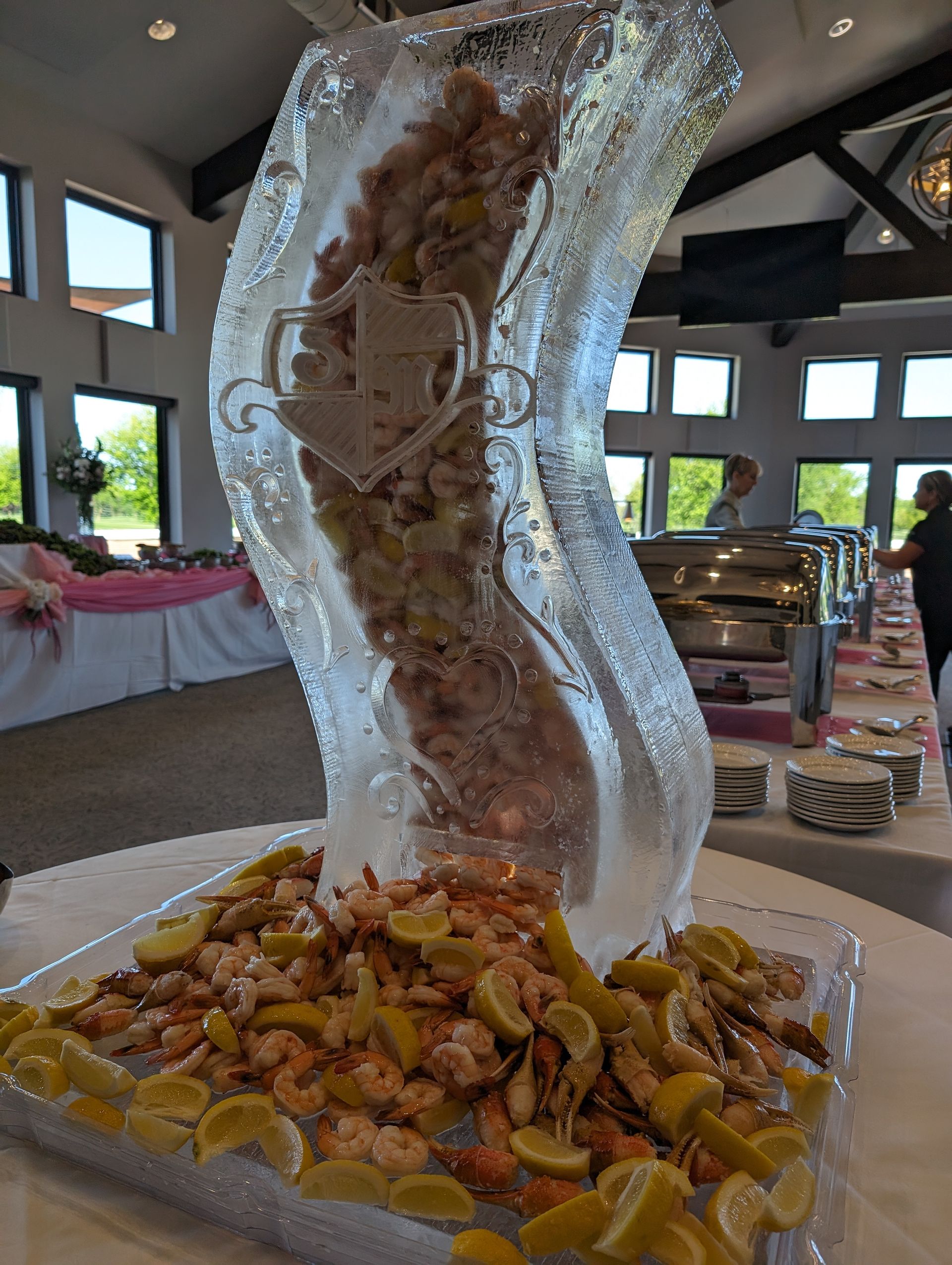 A large ice sculpture filled with shrimp and lemons on a table.
