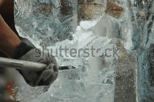 A person is carving an ice sculpture with a hammer.