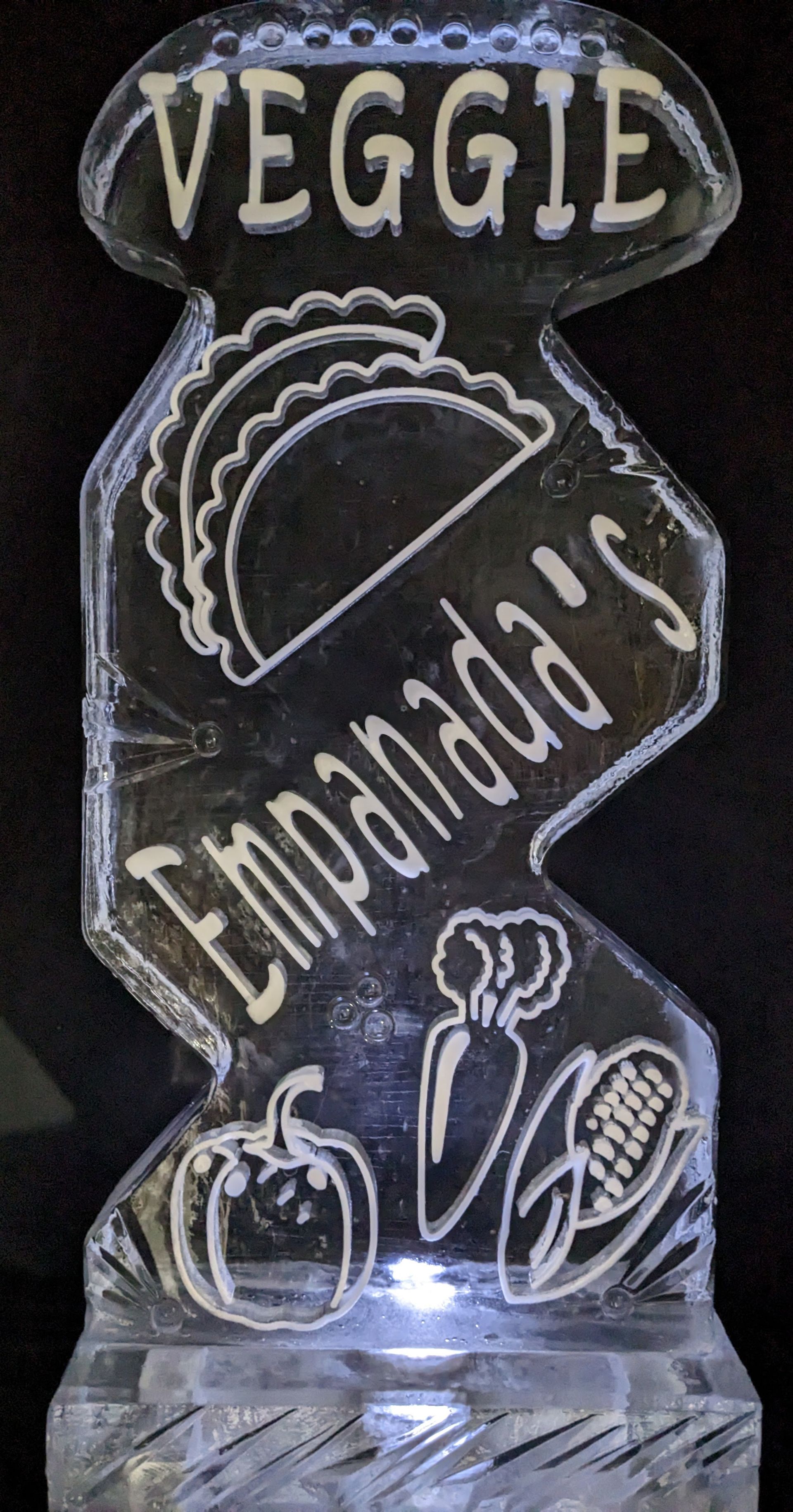 A veggie empanada 's ice sculpture with a taco and vegetables on it.