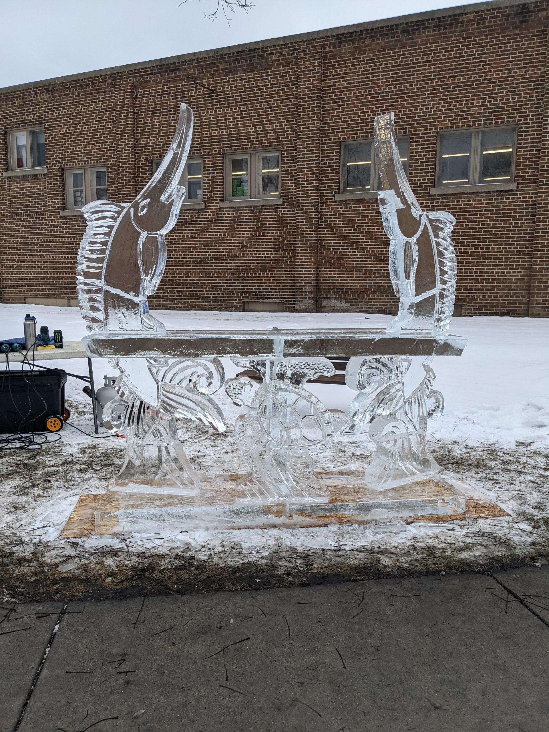 A bench made of ice is sitting in front of a brick building