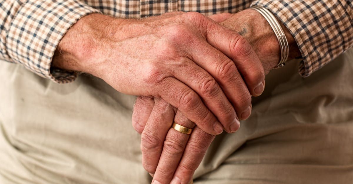 A man with a ring on his finger is holding a cane.