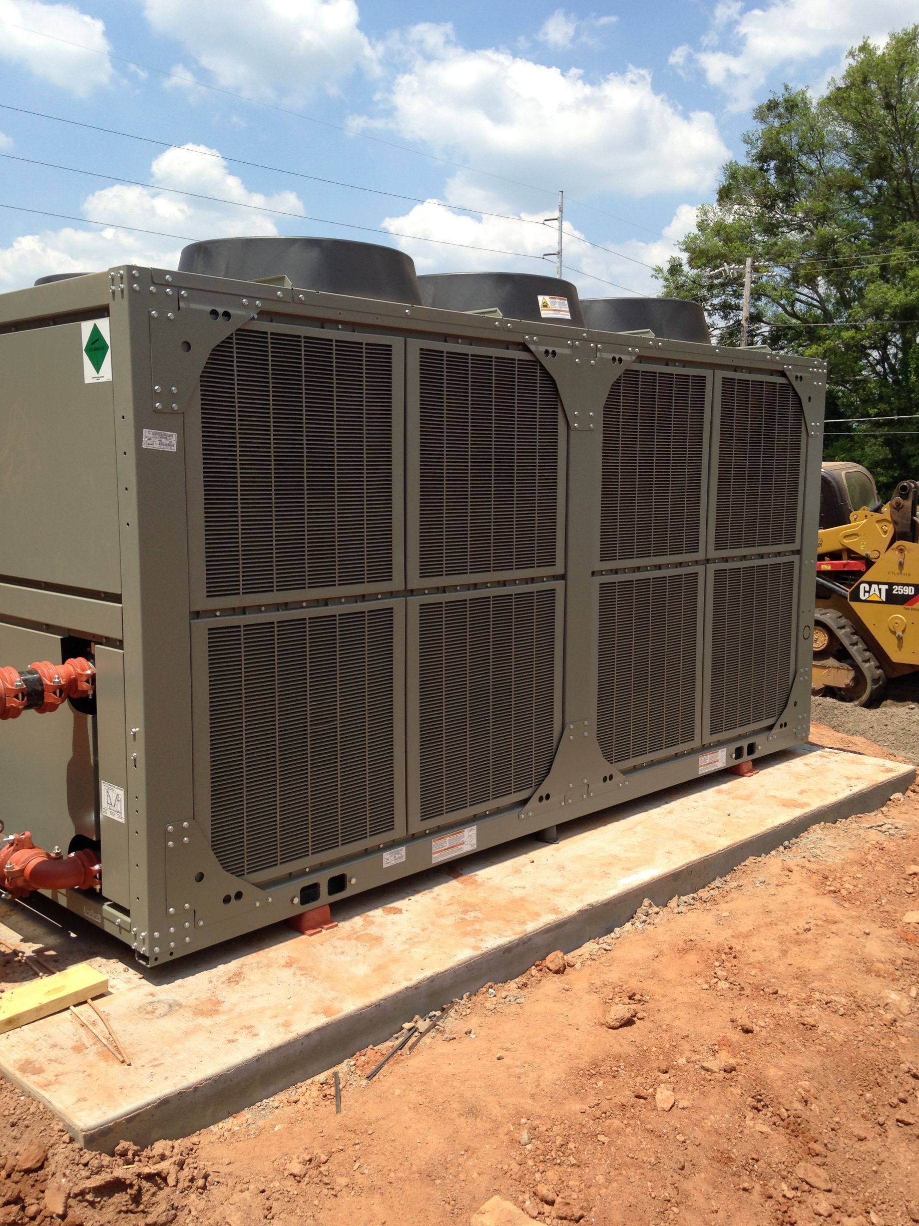 A large air conditioner is sitting on top of a pile of dirt.