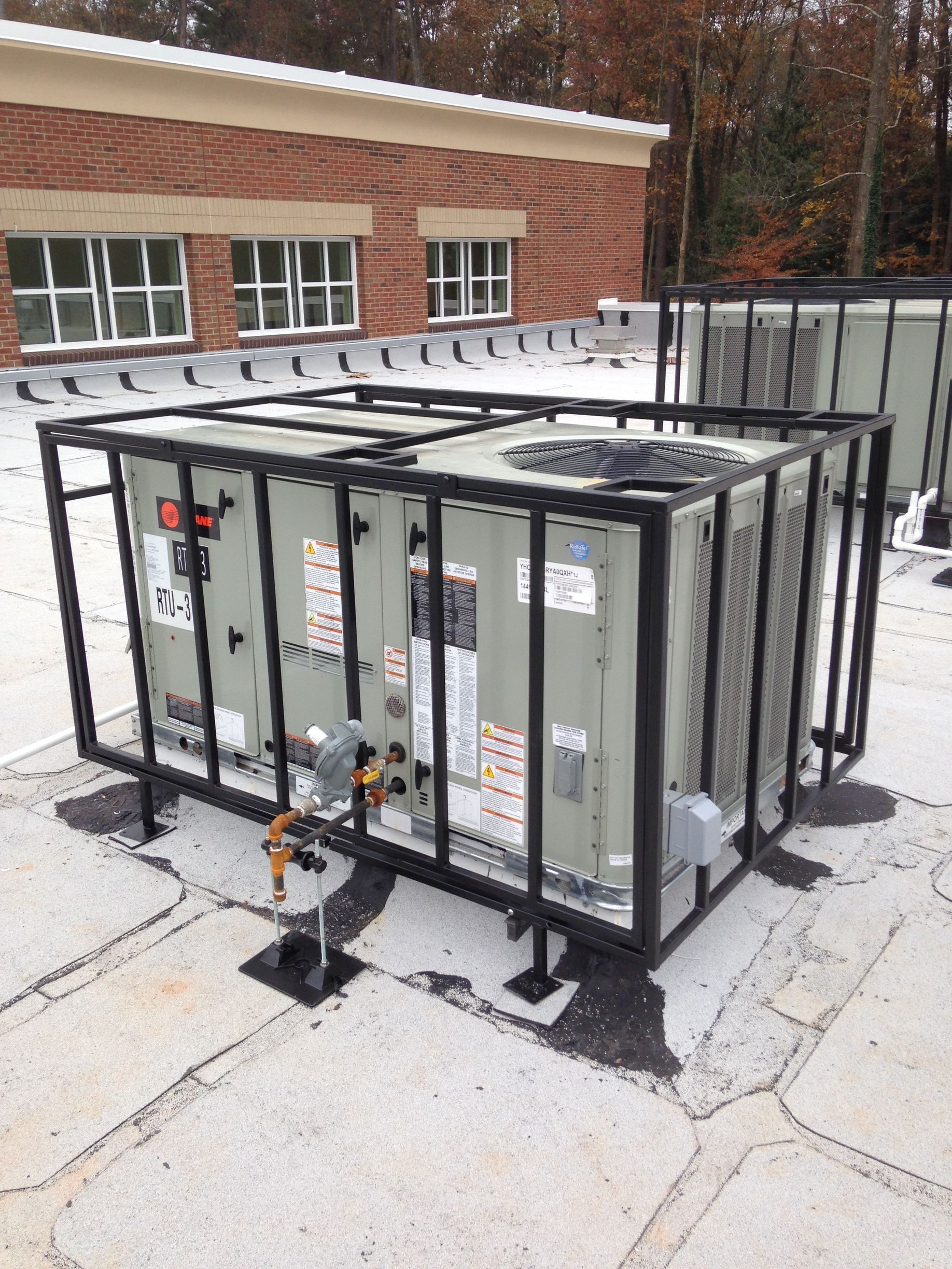 An air conditioner is sitting in a metal cage on the roof of a building.