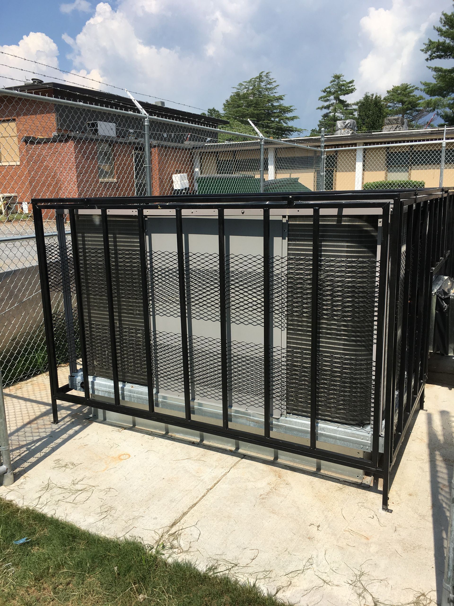 A black metal fence surrounds a building with a chain link fence in the background.