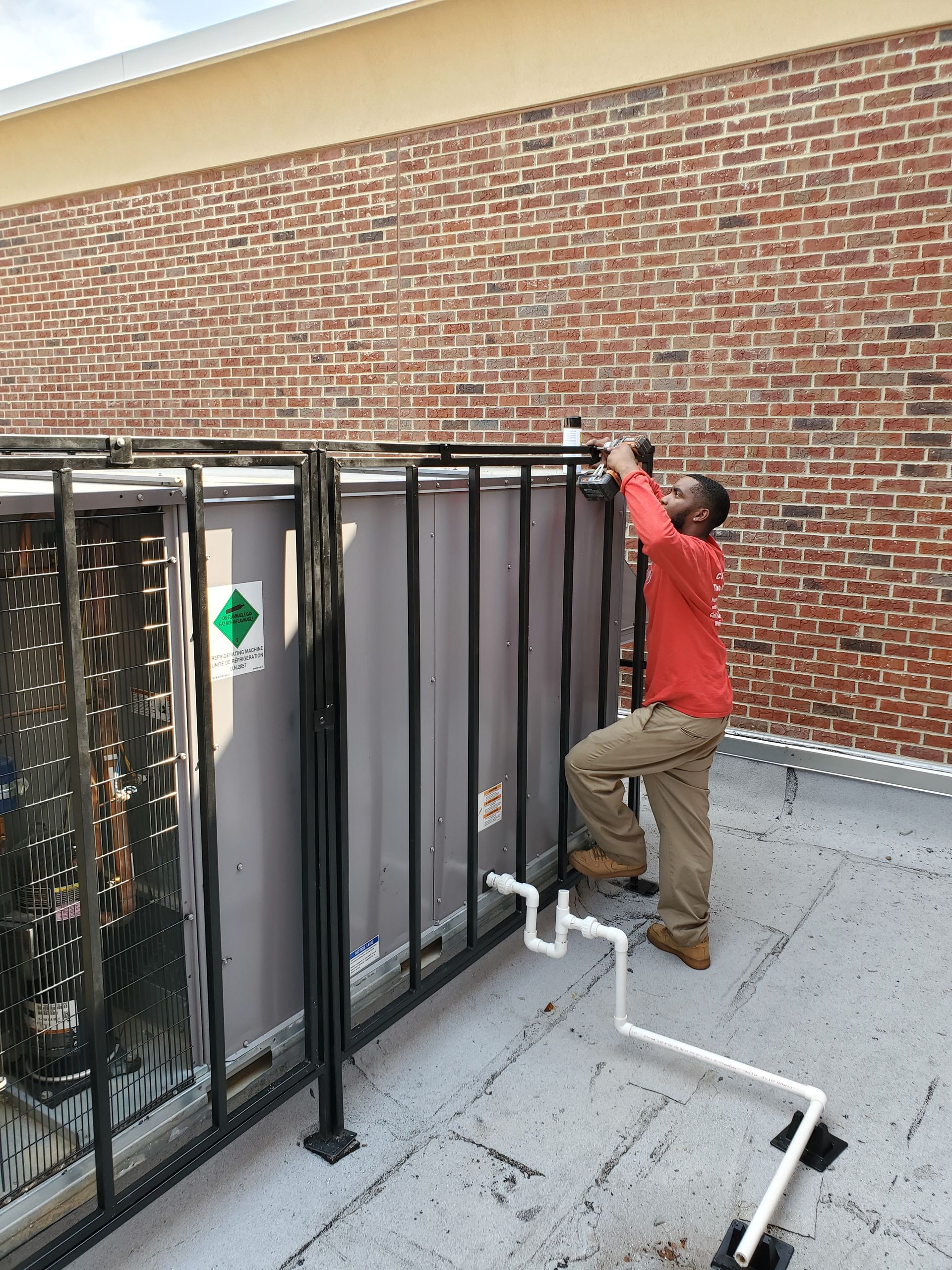 A man is working on a rooftop air conditioner.