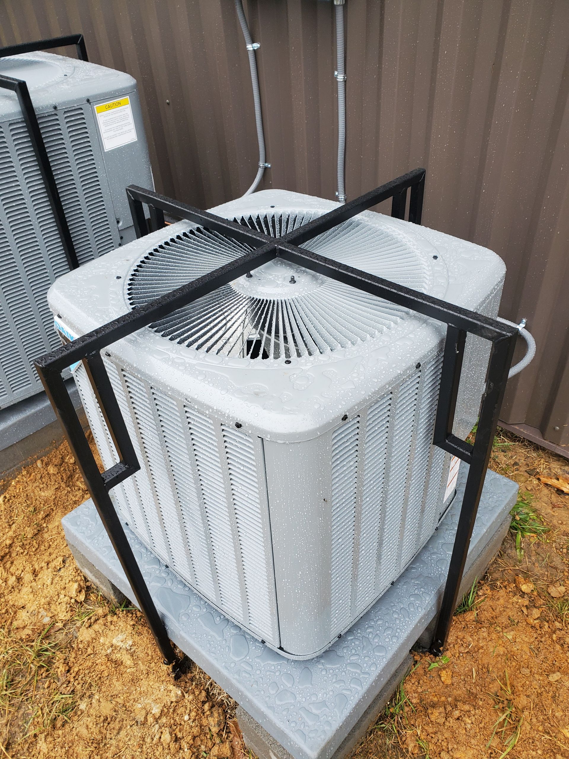 A row of air conditioners are sitting inside of a metal cage.
