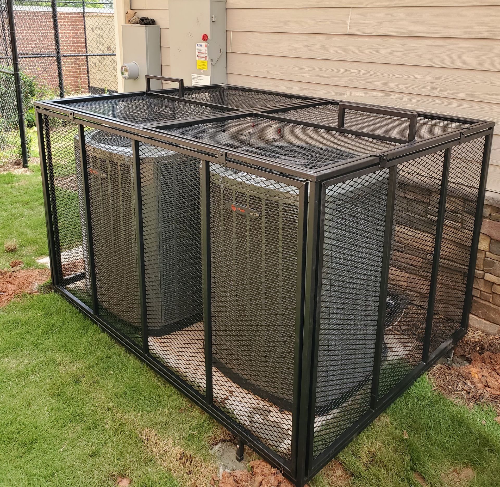 An air conditioner is sitting inside of a metal cage.