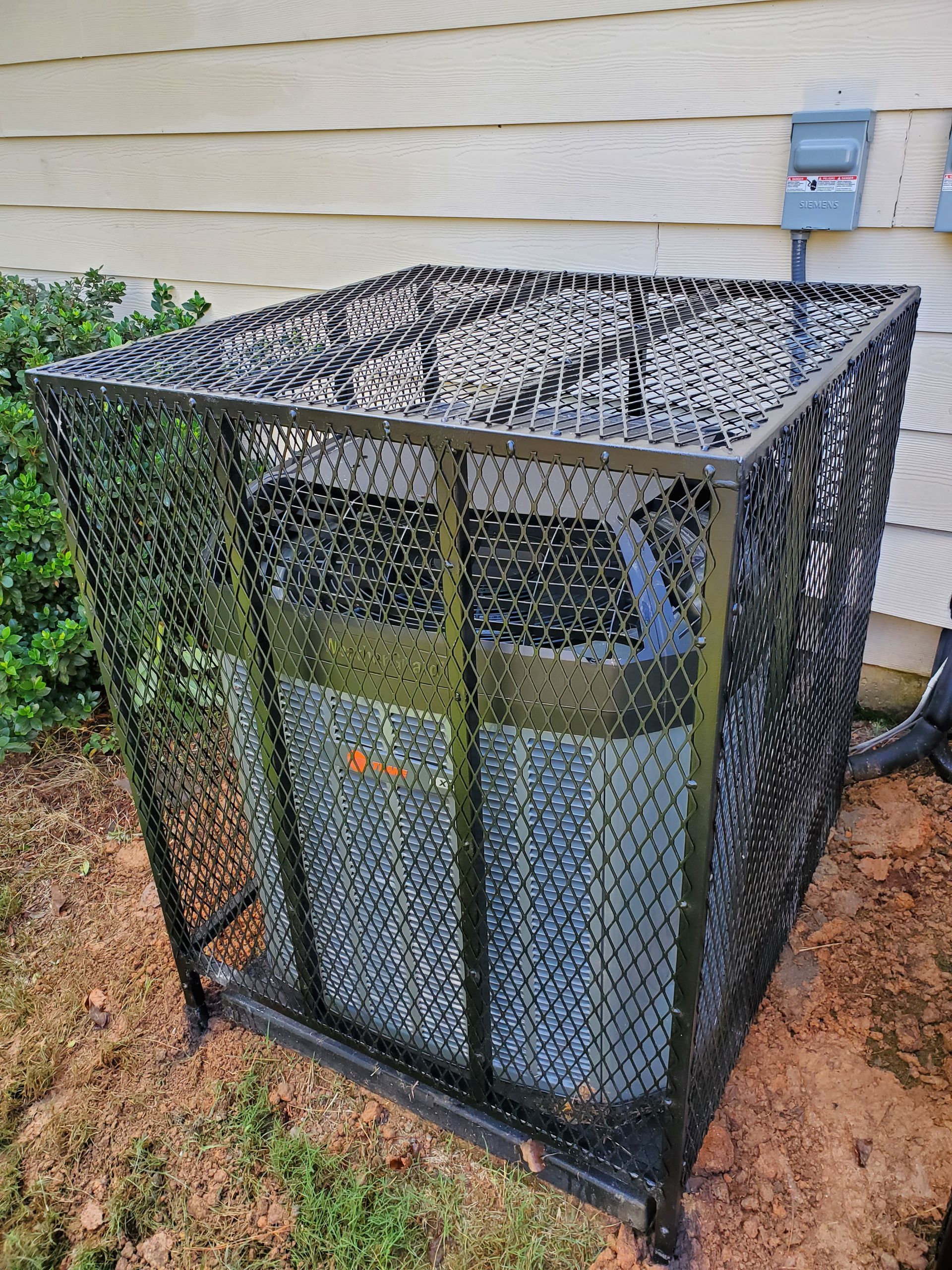An air conditioner is sitting inside of a metal cage.