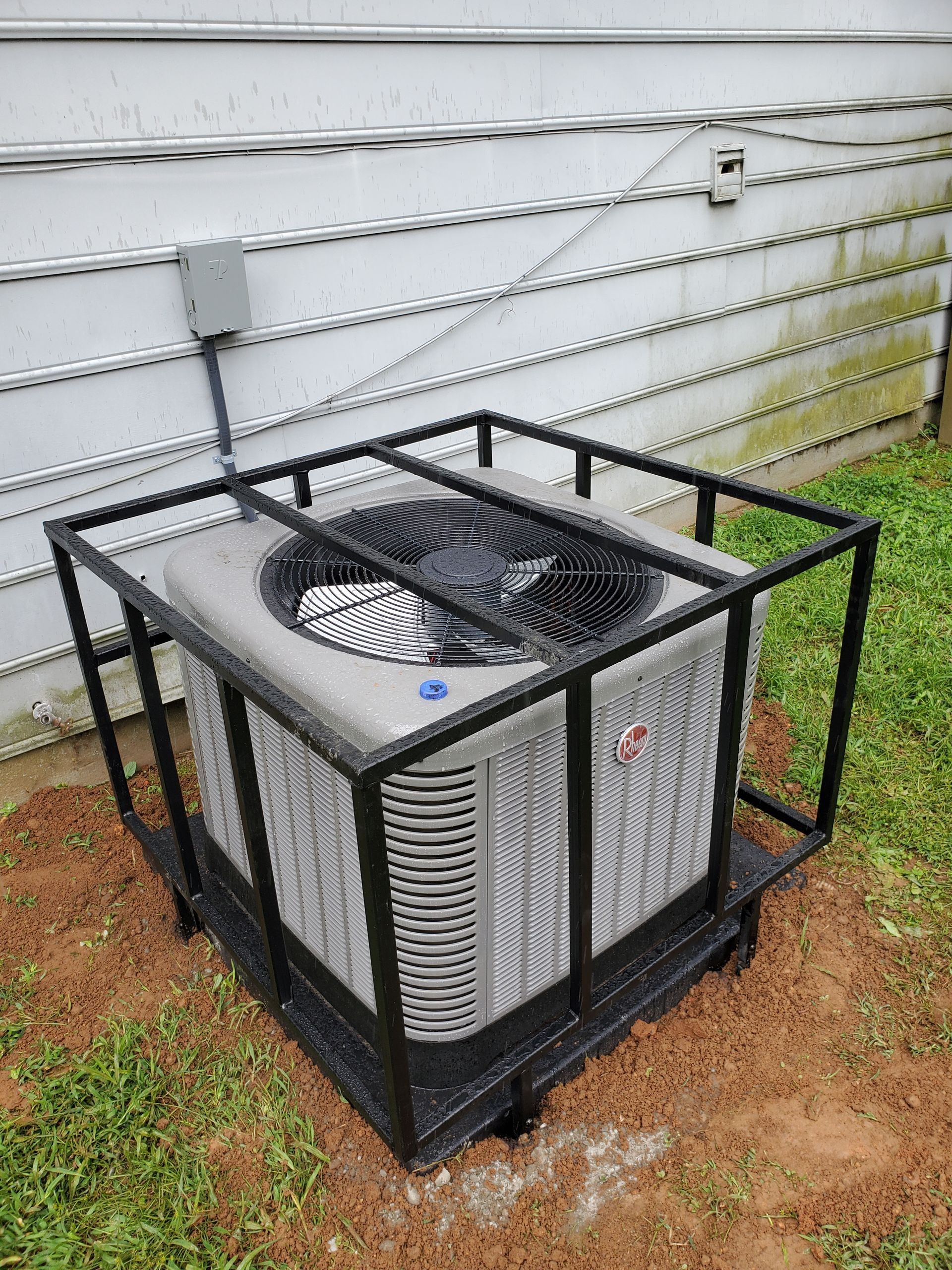 An air conditioner is sitting in a metal cage outside of a house.