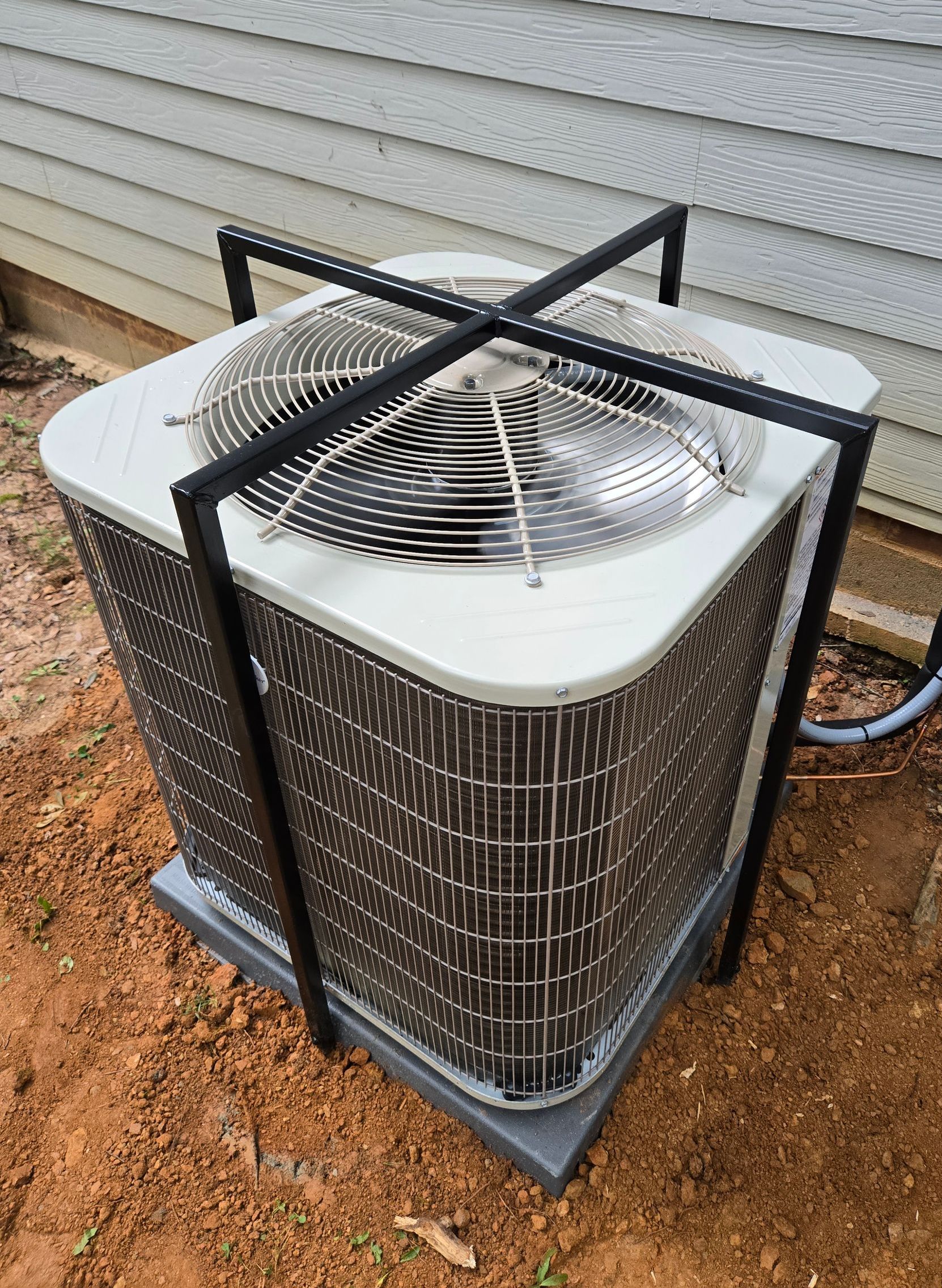 A large air conditioner is sitting outside of a house.
