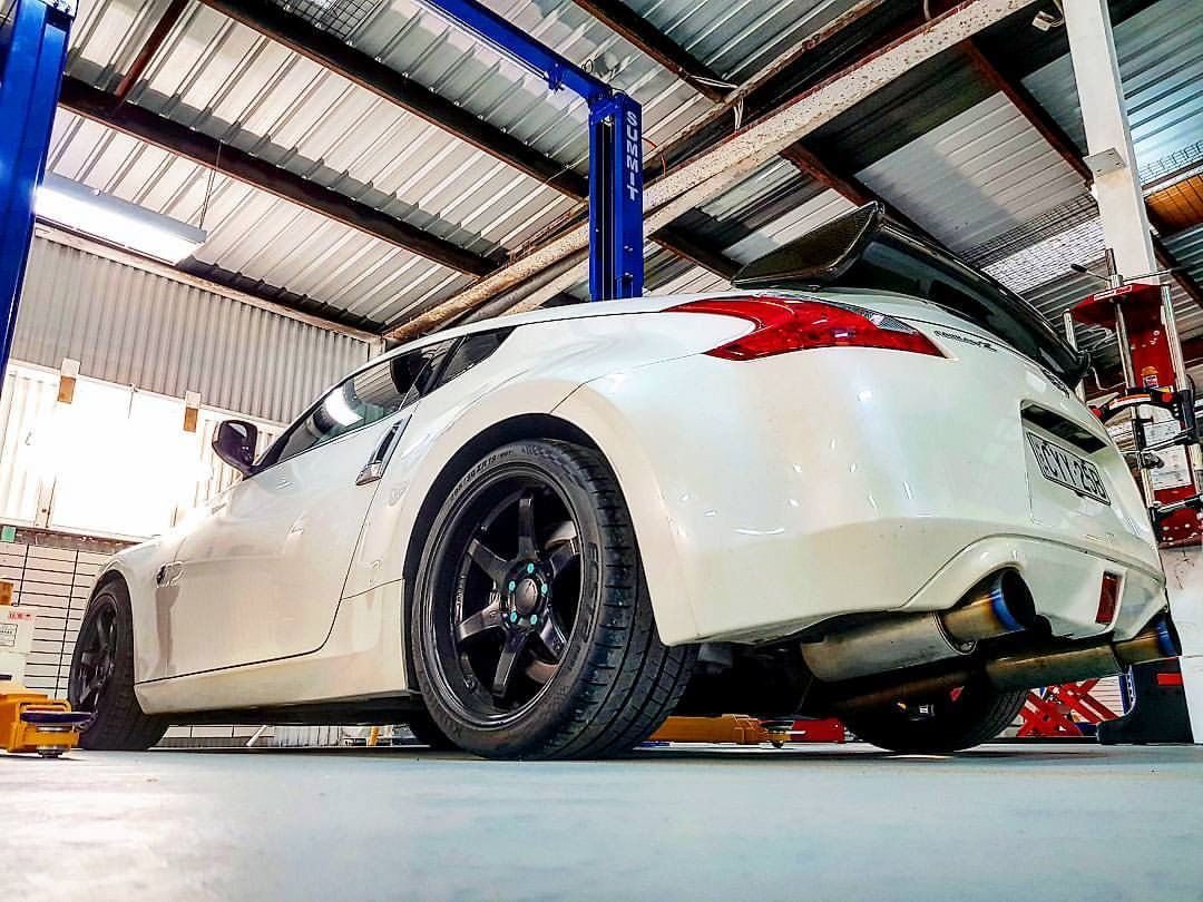 A White Car Is Sitting On A Lift In A Garage — Sojos Mechanical & Tyre Service In West Gosford, NSW