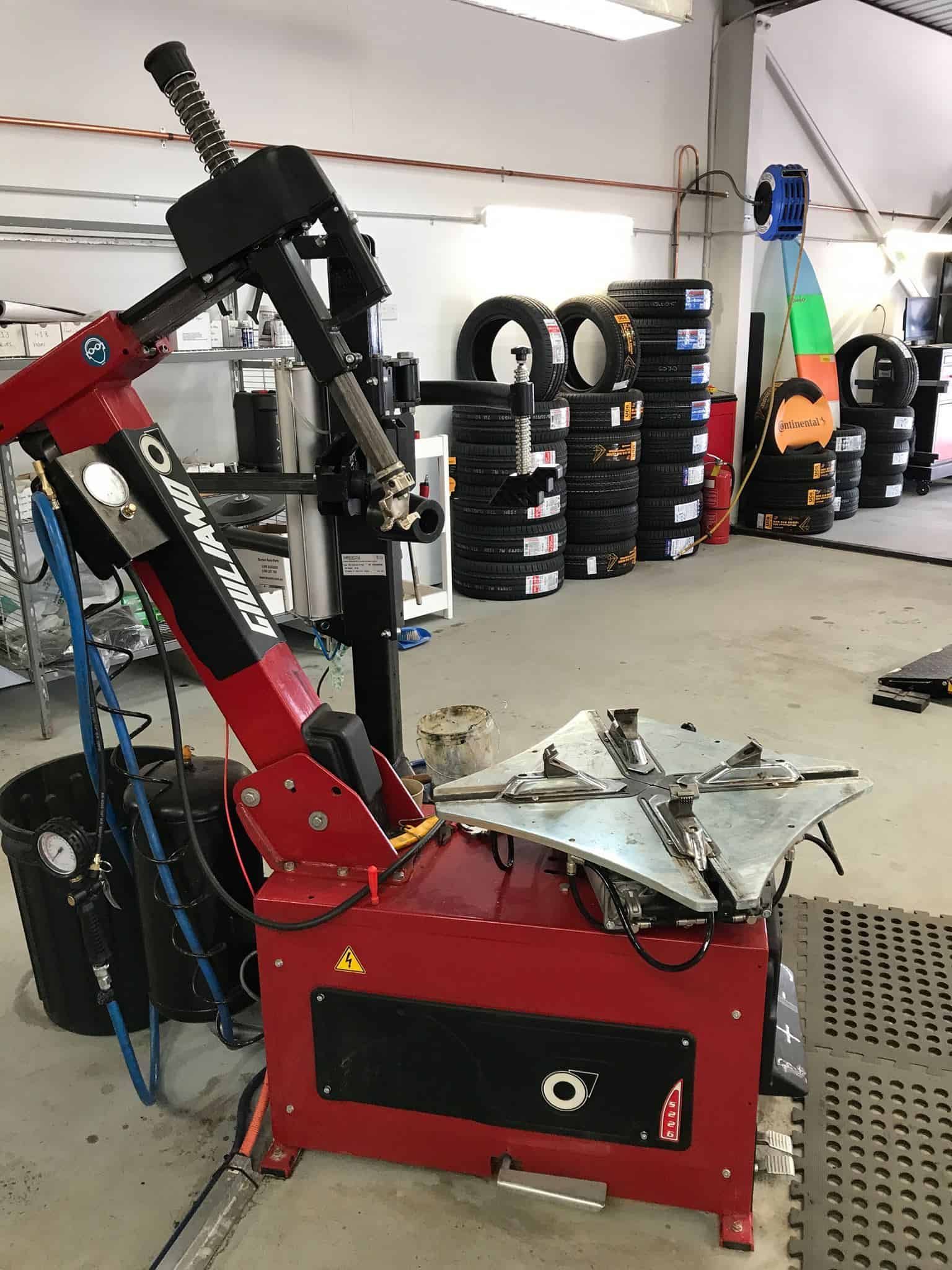 A Tire Changer Is Sitting In A Garage Next To A Stack Of Tires — Sojos Mechanical & Tyre Service In Wyoming, NSW