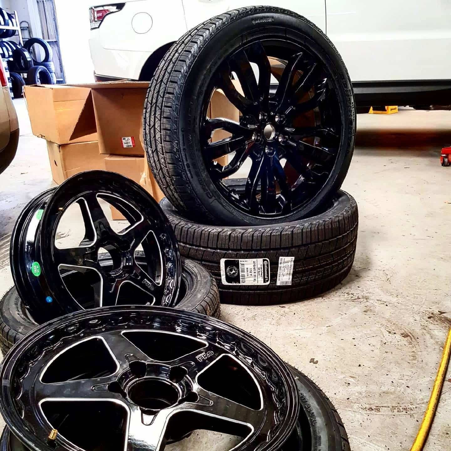 A Bunch Of Tires And Wheels Are Stacked On Top Of Each Other In A Garage — Sojos Mechanical & Tyre Service In Erina, NSW