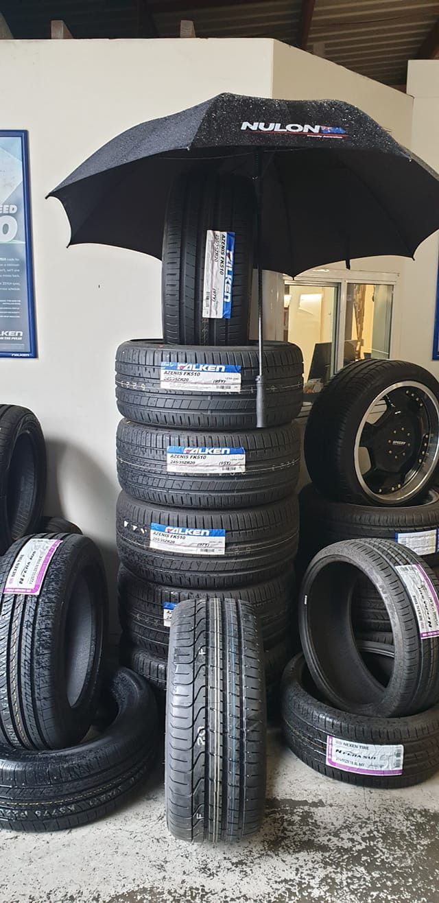 A Black Umbrella Is Sitting On Top Of A Pile Of Tires — Sojos Mechanical & Tyre Service In West Gosford, NSW