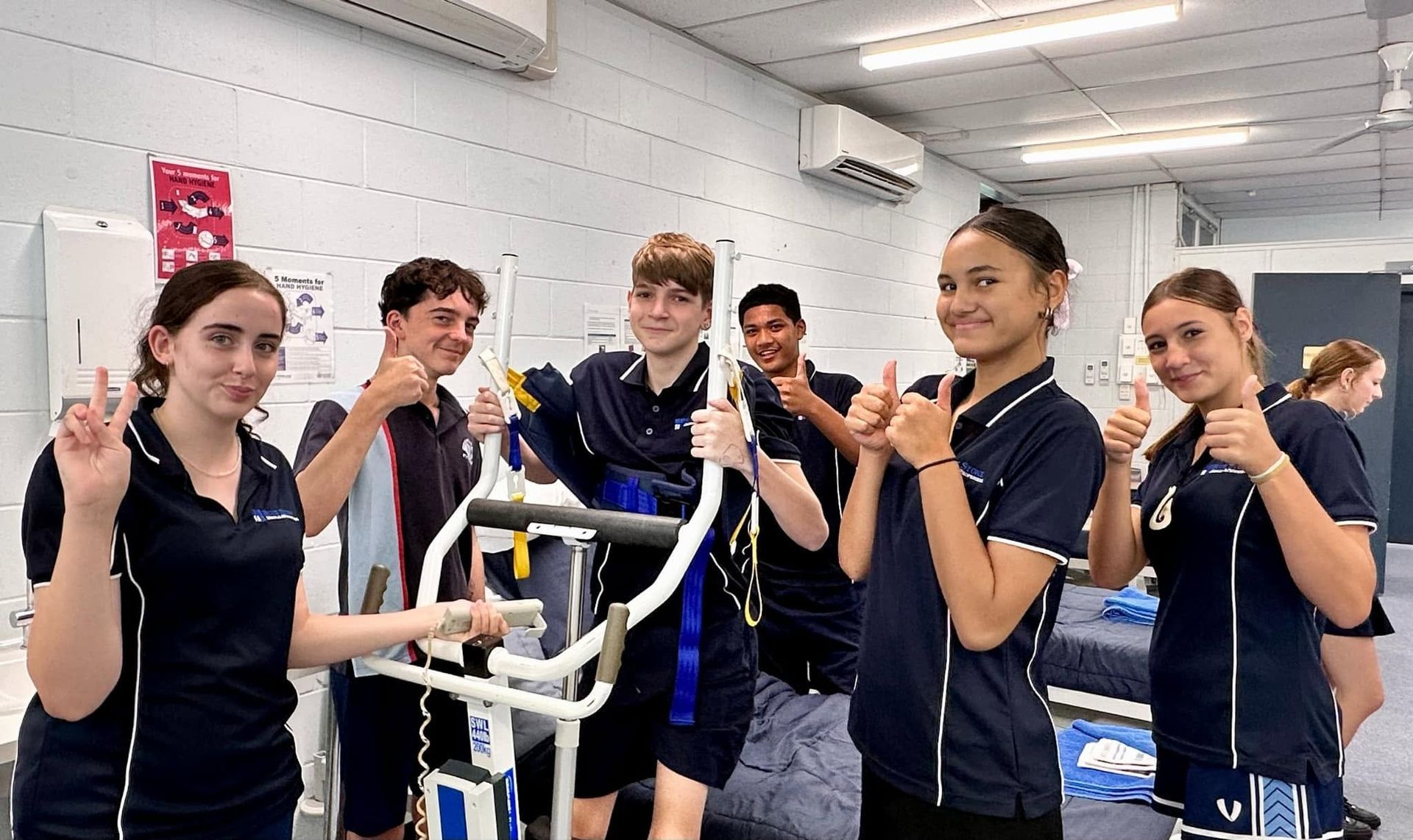 Student — Accredited Training in Rockhampton QLD Group of Students in Blue Scrubs Giving Thumbs-up Beside Lab Equipment — Accredited Training in Rockhampton QLD