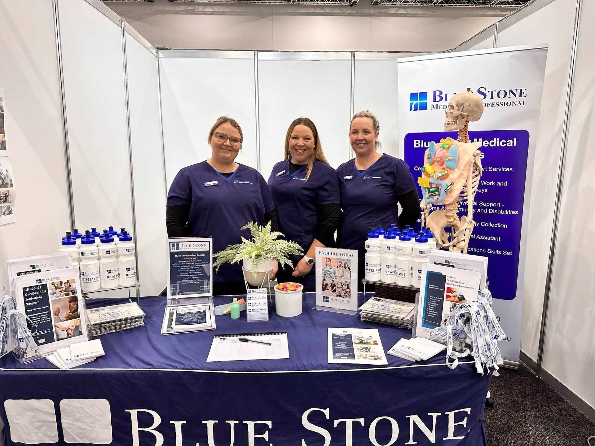 Blue Stone Booth With Three Staff in Navy Shirts Displaying Products — Accredited Training in Rockhampton QLD