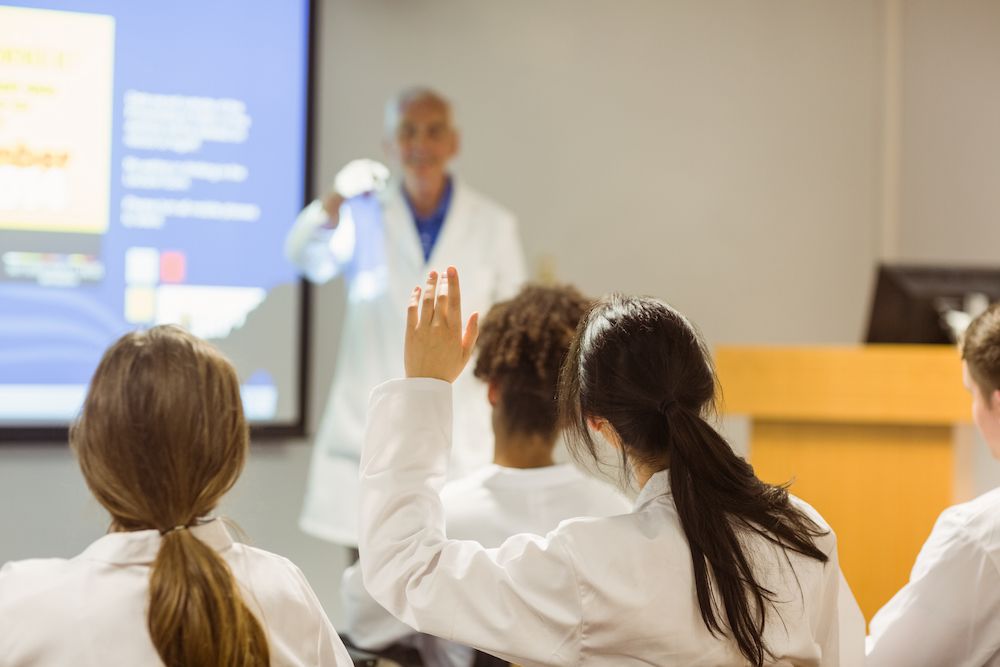 Students in White Coats Raising Hands During a Classroom Lecture — Blue Stone Medical & Professional in West Rockhampton, QLD