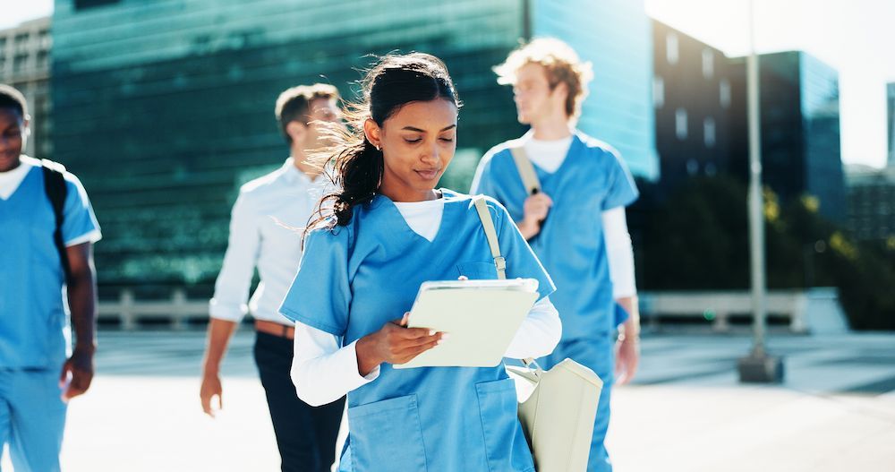 Medical Staff in Blue Scrubs Walking Outdoors While Reviewing a Clipboard — Blue Stone Medical & Professional in West Rockhampton, QLD