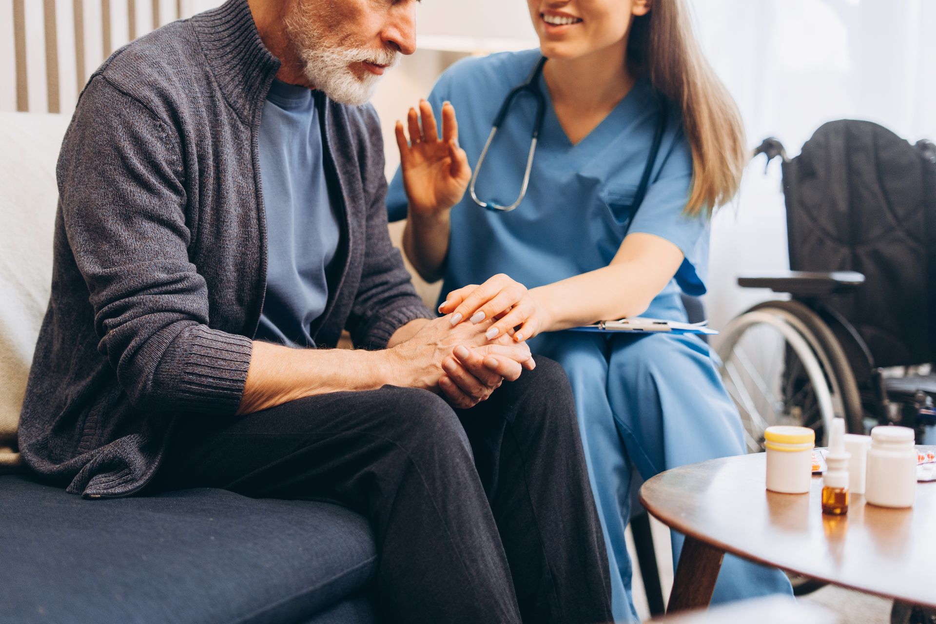 Caregiver in Blue Scrubs Holding Hands With a Seated Patient — Blue Stone Medical & Professional in West Rockhampton, QLD