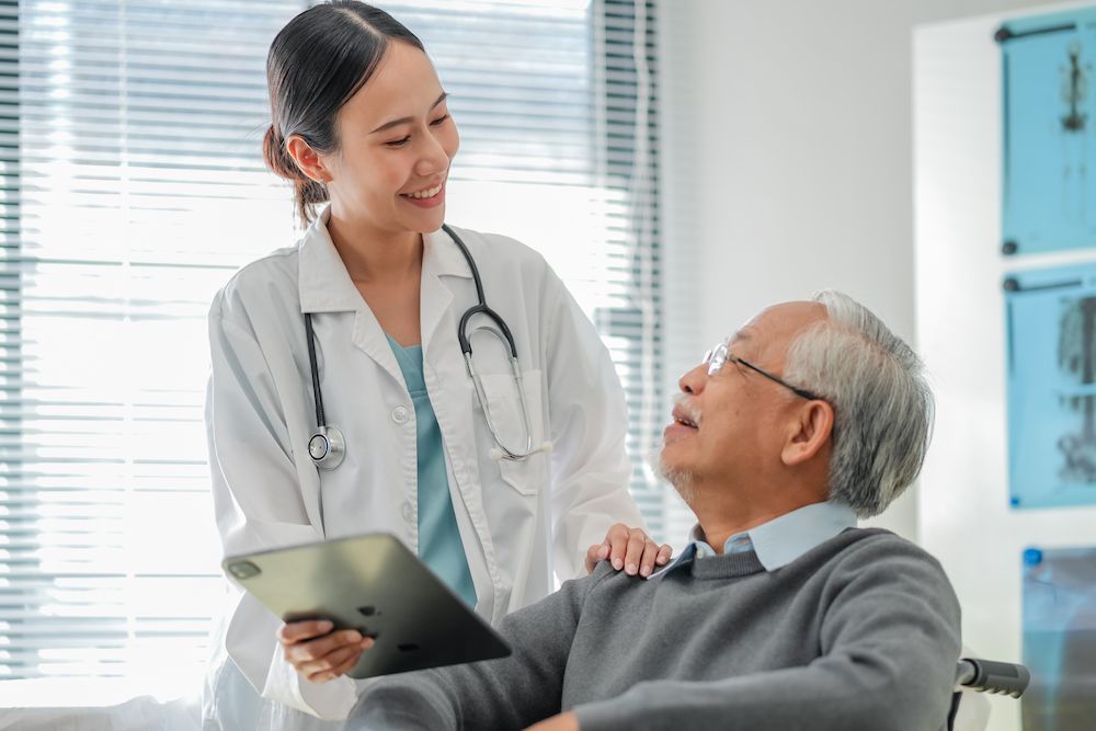 Doctor Smiling and Consulting With a Seated Patient — Blue Stone Medical & Professional in West Rockhampton, QLD