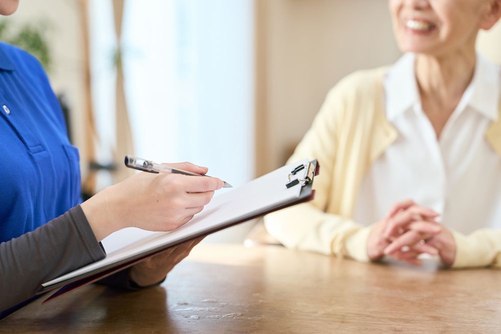 Person Taking Notes on a Clipboard During a Conversation — Blue Stone Medical & Professional in West Rockhampton, QLD