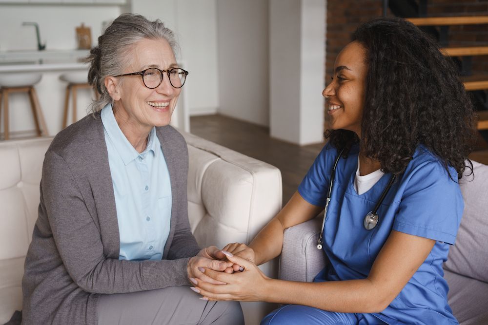 Two Women in a Bright Living Room Holding Hands and Smiling — Blue Stone Medical & Professional in West Rockhampton, QLD