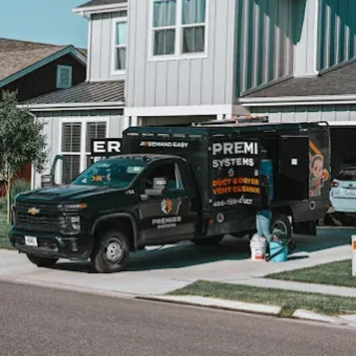 A black Premier Systems work truck parked in a residential driveway, with equipment staged by the open side door.