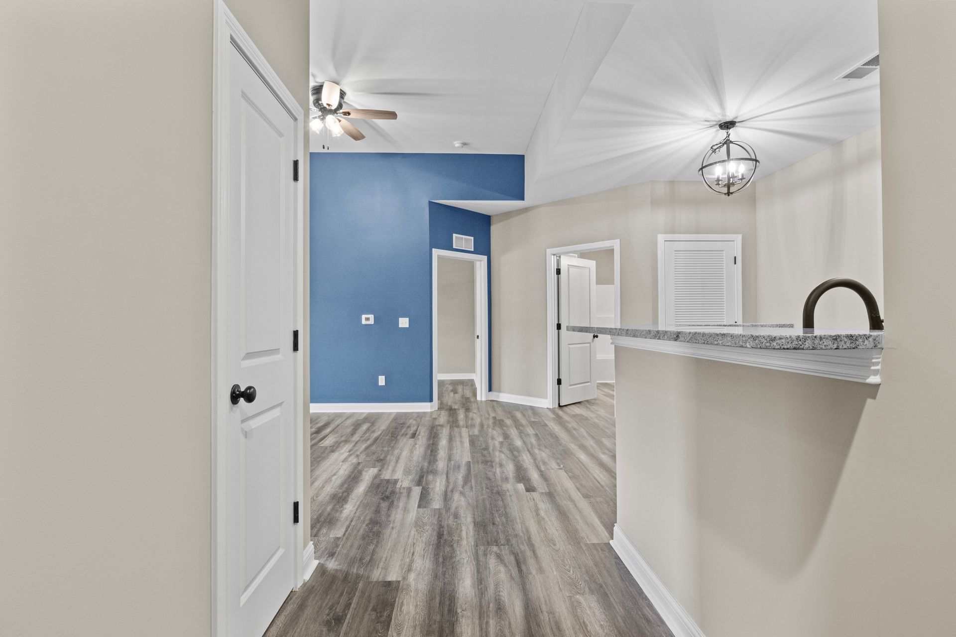 A hallway in a house with hardwood floors and a ceiling fan.