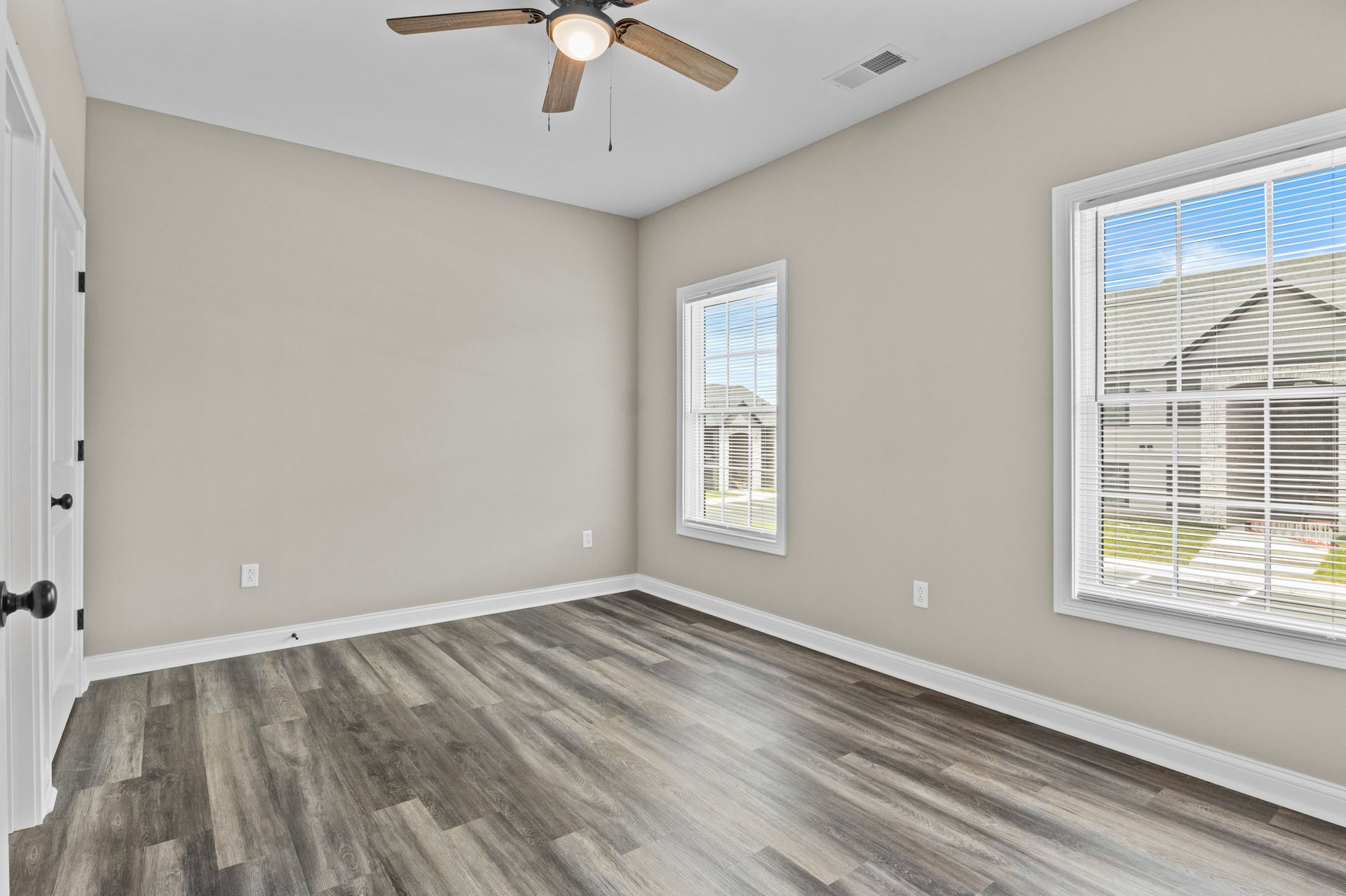 An empty bedroom with hardwood floors and a ceiling fan.
