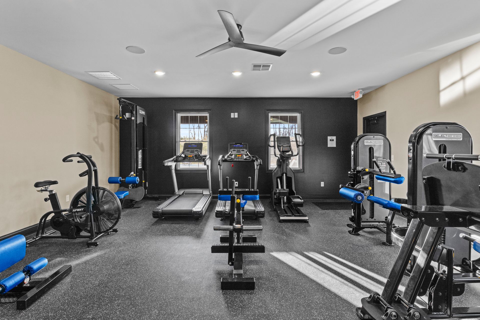 A gym with a treadmill , exercise balls , a boxing bag and a television.