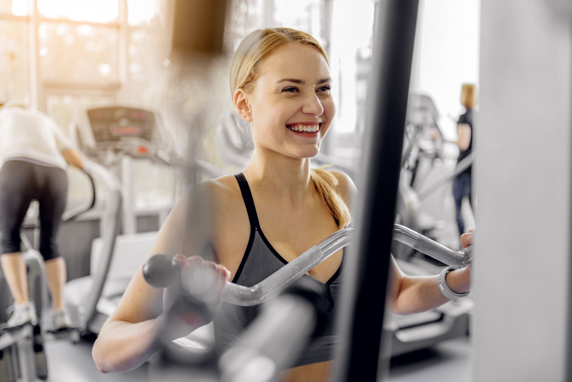 A woman is smiling while using a machine in a gym.